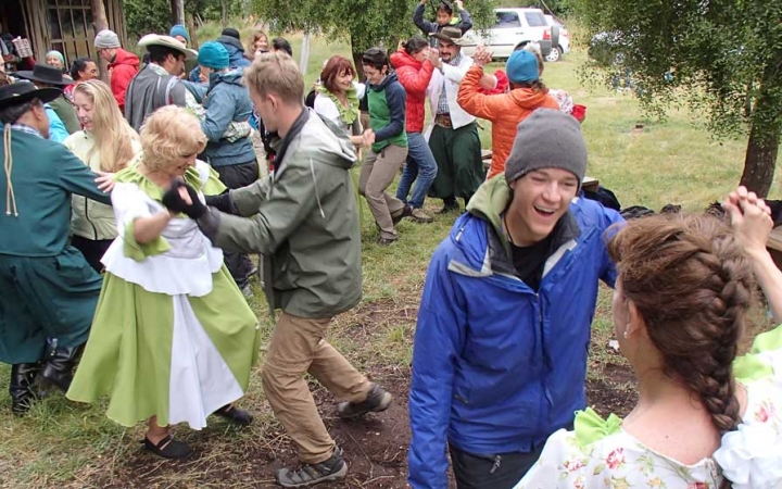 A group of people dance in pairs outdoors. 